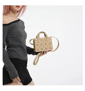 Détail du mini sac beige orné de rivets en motif floral avec poignée et bandoulière