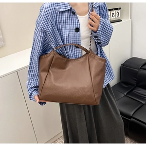 Détail du sac cabas marron foncé avec texture litchi et bandoulière en chaîne métallique