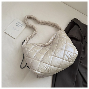 Macro view of cream quilted puffer tote showing pleated strap and shiny nylon texture