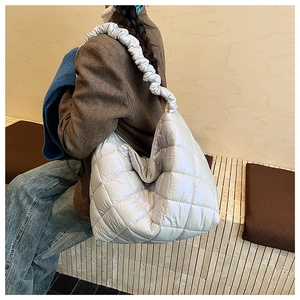 Detail of light blue quilted tote bag featuring ruffled shoulder straps and cloud texture