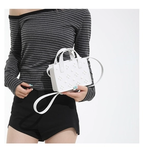 Vue détaillée du mini sac bandoulière blanc en cuir clouté porté par un mannequin