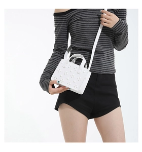 Détail d'un petit sac carré blanc avec relief floral et bandoulière en cuir amovible