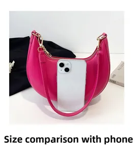 Pink crescent hobo bag shown alongside a smartphone for size comparison and scale