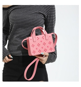 Mini sac carré rose en cuir avec détails de rivets et pétales porté à la main
