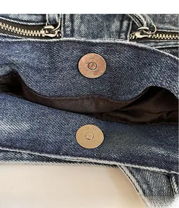 Detail of high-quality metal magnetic clasp and zipper on blue washed denim tote bag