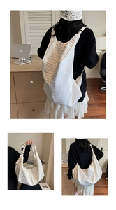 Detail showing white pleated nylon bag with adjustable straps for various carrying styles