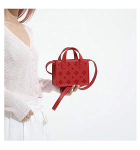 Détail du sac rouge à rivets avec cuir texturé et perles florales 3D sur le sac à main