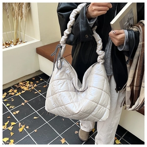 Detail of beige quilted tote bag with puffer texture and drawstring cloud handle