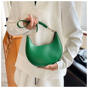 Detailed macro view of vibrant green crescent bag featuring smooth texture and gold buckle