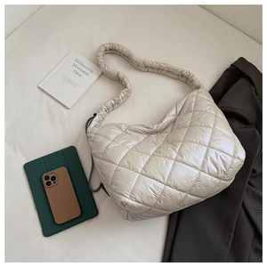 Detailed close-up of a quilted puffer tote bag in beige with gathered shoulder straps