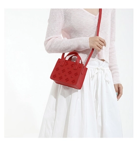 Gros plan d'un sac bandoulière rouge en cuir avec motifs floraux et rivets décoratifs
