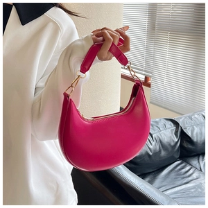 Close-up of pink crescent handbag with metallic gold zipper and leather texture