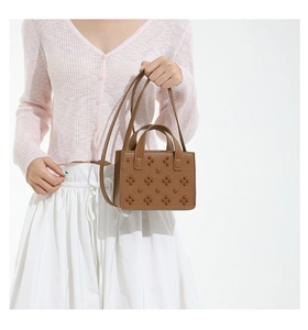 Détail du cuir texturé litchi avec ornements cloutés floraux sur le sac à main marron