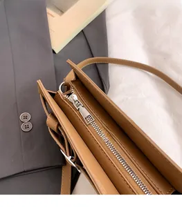 Gros plan du zip en métal argenté et des coutures fines sur le sac à bandoulière brun