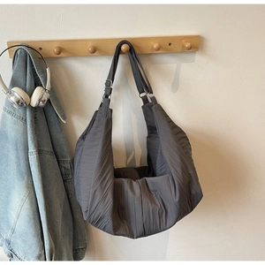 Close-up of pleated dark grey tote bag with puffy texture and adjustable shoulder strap