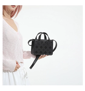 Détail du mini sac noir avec rivets floraux et texture de cuir grainé litchi