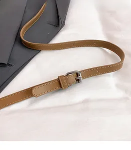 Gros plan sur la bandoulière en cuir marron réglable avec boucle argentée et surpiqûres
