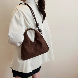 Deep brown suede hobo bag with unique knot detail shown from a side view on a model