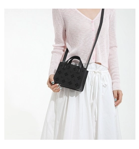 Détail du cuir gaufré trèfle sur un sac bandoulière noir avec sangle réglable