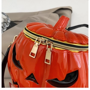 Detail of high-gloss orange pumpkin crossbody bag with golden dual zipper and stitching