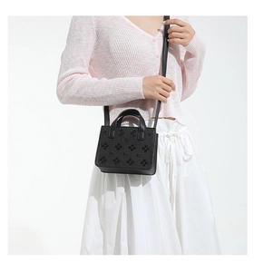 Vue latérale du sac à bandoulière en cuir grainé noir avec rivets floraux 3D