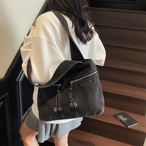 Retro black washed denim tote bag with zipper details worn by a model on stairs