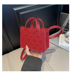 Détail du mini sac cabas rouge en cuir texturé avec clous carrés et bandoulière