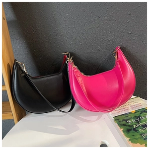 Detail showing classic black and vibrant rose red crescent shoulder bags with gold zippers