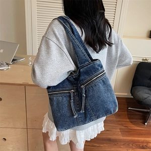 Vintage washed denim tote bag with dual front zipper pockets shown in daily office scene