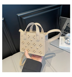 Détail du mini sac à main en cuir beige texturé avec motif géométrique de rivets