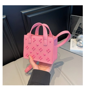 Gros plan du mini sac cabas rose à rivets en cuir avec poignée carrée assortie