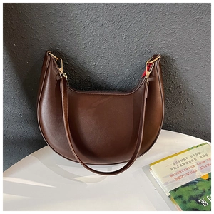 Detail view of brown crescent shoulder bag with golden hardware and smooth zip closure