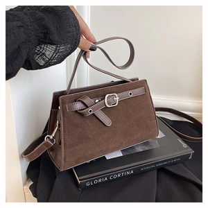 Détail du sac à main en daim marron foncé avec boucle de ceinture et finitions argent