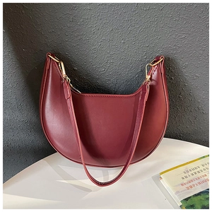Detailed macro shot of a burgundy half-moon leather shoulder bag with gold metal buckle