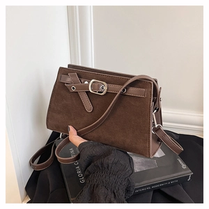 Détail du sac bandoulière en daim marron foncé avec boucle décorative et ferrures