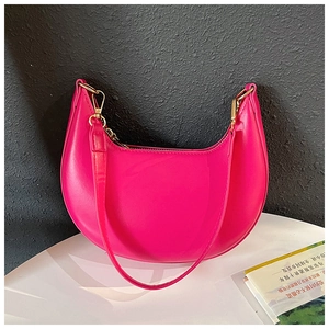 Detail of bright pink crescent shoulder bag with golden zipper and sleek leather strap