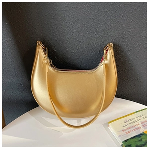 Detail view of metallic gold crescent bag with smooth zipper and red fabric lining