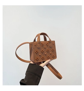 Détail du sac à bandoulière en cuir marron grainé avec décoration de rivets ronds