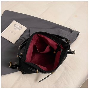 Interior view of black shoulder bag with deep red lining and functional pockets