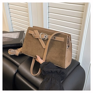 Détail d'un sac à bandoulière en daim marron avec boucle en métal argenté et cuir lisse
