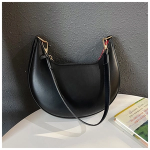 Detail view of black crescent shoulder bag with golden buckle and red inner lining