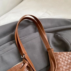 Detail of brown woven faux leather tote with metallic ring and smooth shoulder strap