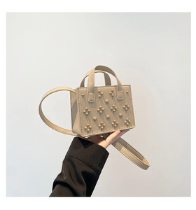 Détail du sac à bandoulière en cuir beige avec rivets en étoile et poignée supérieure