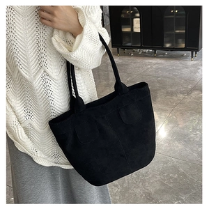 Detail of black suede tote bag showing double shoulder straps and soft texture finish