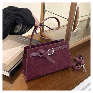 Gros plan d'un sac à bandoulière bordeaux en cuir mat avec boucle et sangle amovible