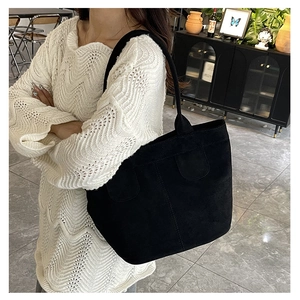 Black suede tote bag styled with cream knit sweater in a cozy indoor lifestyle setting