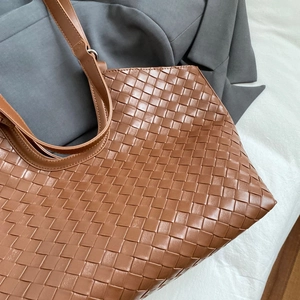 Detail of tan woven leather tote bag featuring signature Intrecciato texture and top handles