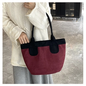 Macro detail of high-capacity suede tote bag with burgundy body and black stitching