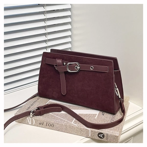 Détail du sac bandoulière en daim bordeaux avec boucle argentée sur rebord de fenêtre