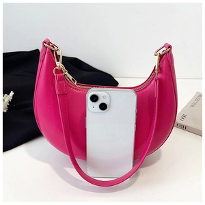 Magenta crescent shoulder bag size comparison with a white smartphone on table